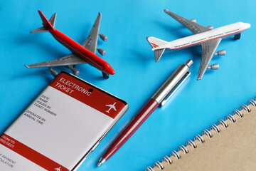 Toy passenger airliners next to an electronic air ticket on smartphone screen, notepad and pen....