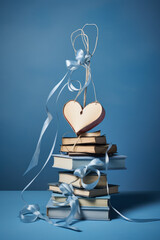Aesthetic composition of books with heart shaped decoration on a pastel light blue background. Education and knowledge  concept. For book lovers.
