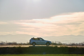 SUV car driving fast on intercity road at sunset. Highway traffic in evening