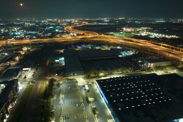 View from above of many parked cars on illuminaded parking lot at night in front of a superstore. Place for vehicles in front of a shopping mall center