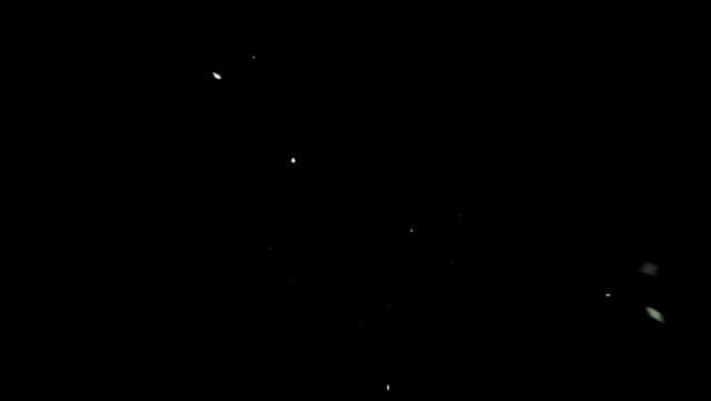 Bottom view isolated slow motion macro shooting capturing lots of grains, granules of salt falling down to the camera from above. Black background.