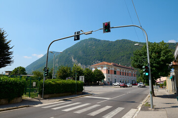 Pedestrian crossing, crosswalk and traffic light in the town of Canso in Lombardy, with the Alps...