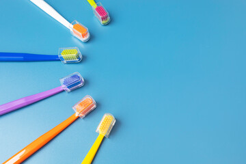 Flat Lay Few of Multicolored Toothbrushes Lying in Shape Of Sun On Blue Background, Space For Tex. Morning hygiene, Bathroom accessories. Dental Health Care. Horizontal Top View Plane