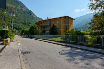 A road in Italian town in Lombardy with view of a residence or mansion against Italian Alps...