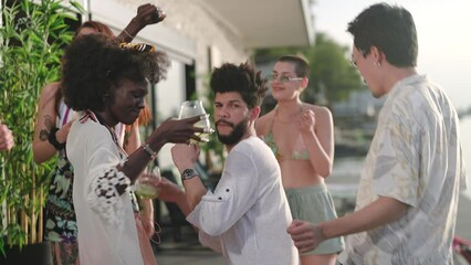 Young and diverse group of friends dancing and having drinks on vacation in their rented lake house