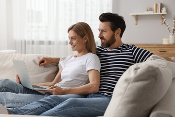 Obraz premium Happy couple with laptop on sofa at home