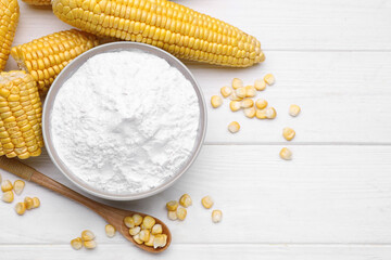 Bowl with corn starch, ripe cobs and kernels on white wooden table, flat lay. Space for text