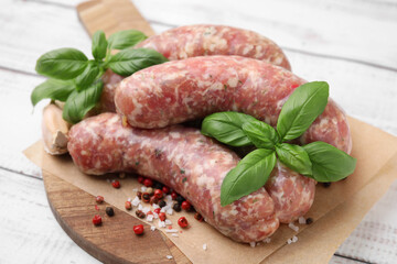 Raw homemade sausages and different spices on white wooden table, closeup