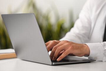 Man using modern laptop at desk in office, closeup