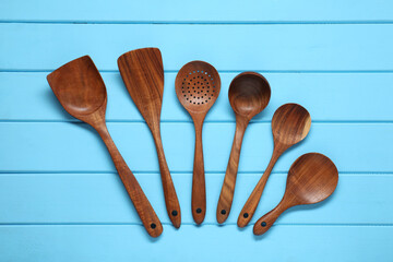 Set of wooden kitchen utensils on light blue table, flat lay