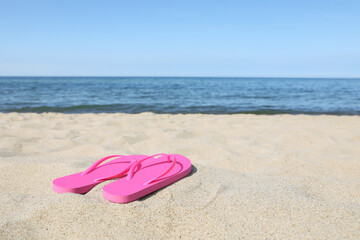 Stylish pink flip flops on beach sand, space for text