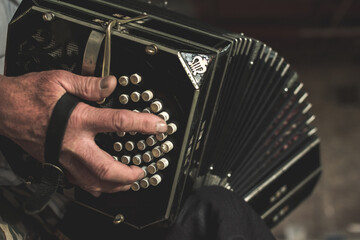 Aged male with white shirt and a wrinkled hand playing on bandoneon - obrazy, fototapety, plakaty
