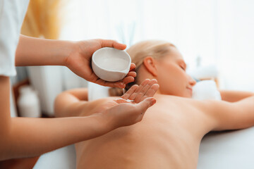Masseur hands pouring aroma oil on woman back. Masseuse prepare oil massage procedure for customer...