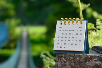 April 2024 calendar with green blurred background of hanging bridge. - obrazy, fototapety, plakaty