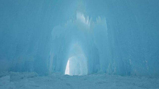 Inside ice tunnel with icicles hanging from ceiling