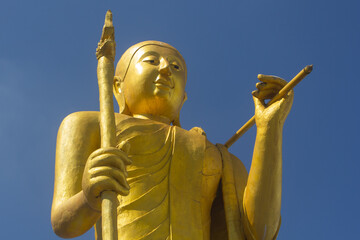 golden thai monk statue with blue sky