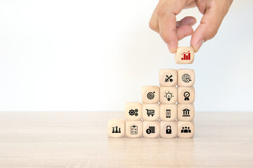 Hand choose cube wooden block stack pyramid with graph and business strategy icon for target goal to growth and financial marketing analysis or human resource management and investment concepts.