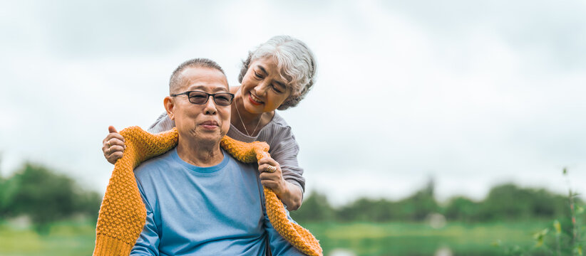 Love and support within an Asian family as they care for their elderly parents, symbolizing values of respect and devotion in aging together. Loving Care for Elderly Asian Couple in Wheelchair