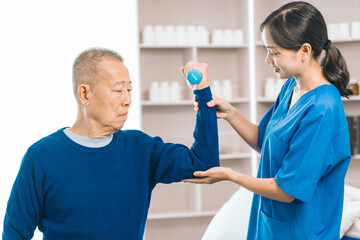 Asian people caregiver provides gentle support and encouragement to an elderly man during physical therapy session in a nursing care facility, promoting strength, mobility, and well-being.