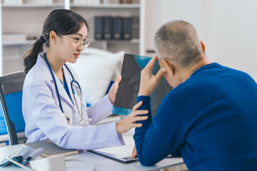 Fototapeta premium Asian people experienced female doctor giving advice to elderly male patient cancer and x-ray results and treatment options, Cancer Consultation, Elderly Man Receives Expert Cancer Advice Awareness
