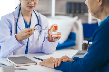 Asian people female dentist imparts valuable advice to elderly male patient, discussing root canal...