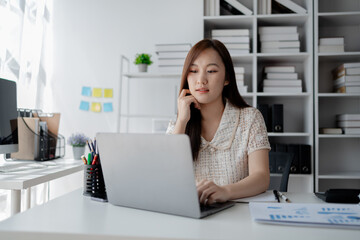 Obraz na płótnie Canvas Young Asian woman, businesswoman in finance, businesswoman working in finance, planning finances for a startup company and reviewing financial statements. Financial management concepts.