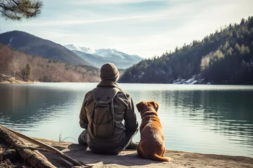 Fotobehang Rear view of man traveler and his dog looking at mountain lake on sunny day © boxstock production