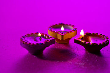 Close up of three diwali candles with copy space on purple background
