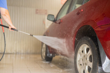 After washing, the man covers the car with protective wax. The driver washes the car after a long...