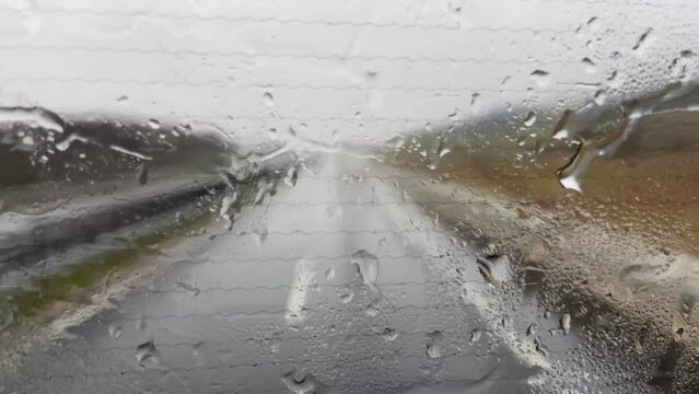 Blur image with rain on the highrway, heavy rain on the windshield, windscreen whilst driving on the motorway in a car, van, truck, dangerous driving conditions, bad weather