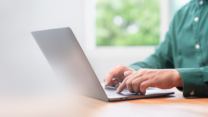 Freelancer use laptop working in late morning. Male hands typing on laptop computer keyboard. Business and technology concept of entrepreneur work, work from home, businessman working at home office.