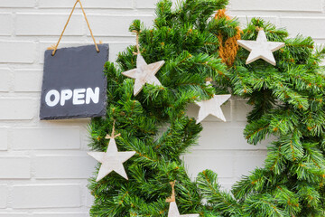 Open sign on a blackboard next to a Christmas wreath