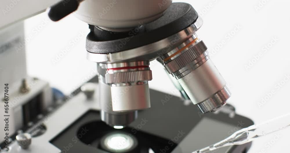 Poster video of close up of laboratory microscope with copy space on white background