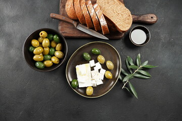 Olives, Olive oil and olive branch, and feta on dark background