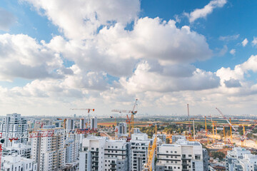 Rishon LeZion, Israel, September 20, 2023. Panorama of a large number of tower cranes, and development of new high-rise apartments against the backdrop of a blue sky and beautiful white clouds