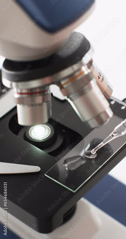 Poster vertical video of close up of laboratory microscope with copy space on white background