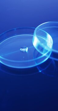 Vertical video of close up of laboratory round glass dishes with copy space on blue background