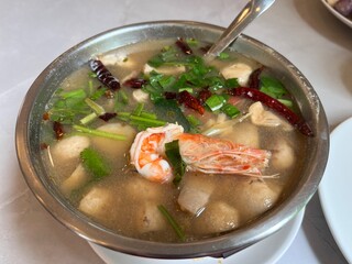 Traditional spicy Tom yum seafood soup dressing with dried chilly and fresh organic mushroom serving in the hot pot. Famous hot and sour soup menu in Thai restaurant.