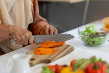 healthy food, weight loss concept beautiful asian muslim woman Attractive woman in headscarf prepares delicious food at kitchen, chopping carrots to nourish skin health care concept