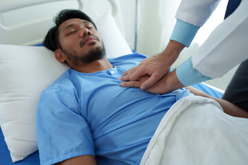 Obraz premium A male doctor uses his hands to pump a patient's heart with basic CPR in an emergency. Lying unconscious in bed. Unconscious. Cardiac arrest. Intensive care treatment concept.