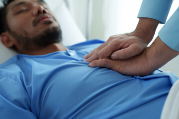 A male doctor uses his hands to pump a patient's heart with basic CPR in an emergency. Lying unconscious in bed. Unconscious. Cardiac arrest. Intensive care treatment concept.