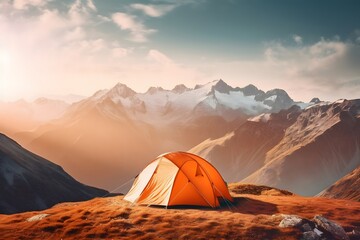 Orange tent on the background of mountains at sunset