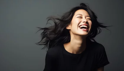Fotobehang Smiling asian woman with wind in her black hair in studio © terra.incognita