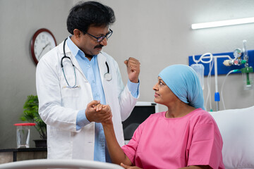 Indian senior doctor consoling or encouraging woman cancer patient by giving confidence at hospital...