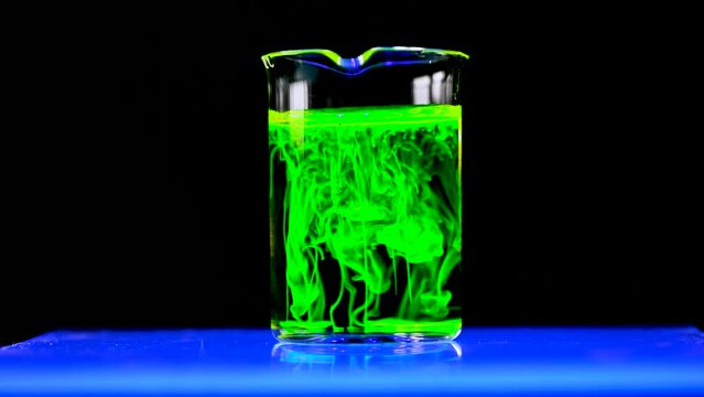 Fluorescent toxic substance dissolving in the chemical solution. The scientist conducts demonstration experiments with solutions. The phenomenon of brownian motion fluorescence.