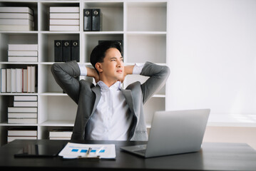 Naklejka premium Overworked young Asian businessman office worker suffering from neck pain after had a long day at desk. office syndrome concept