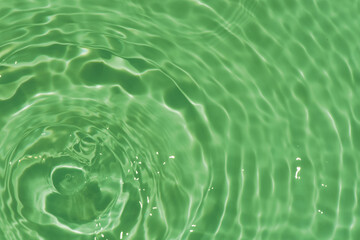 Defocus blurred transparent green colored clear calm water surface texture with splashes...