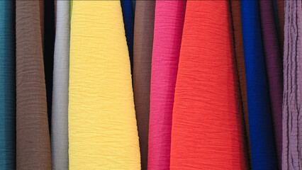 Mix colorful hanging vertical stripe textile, fabrics, cloths on the rack. Texture of multicolored fabrics close up.