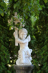 A statue of an angel with a cross in an old cemetery.