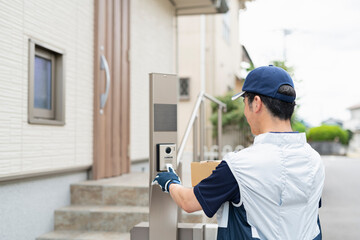 家のインターホンを押す40代配達員